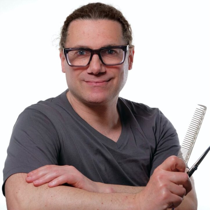 A man with glasses holding a comb and posing for the camera.